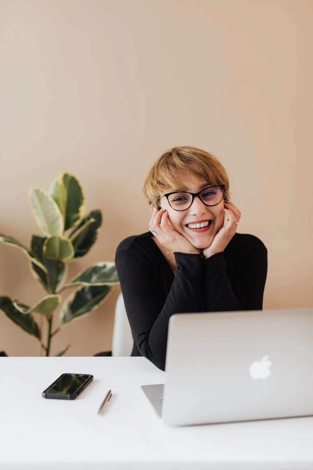 head in hands business woman at laptop with her head in her hands smiling